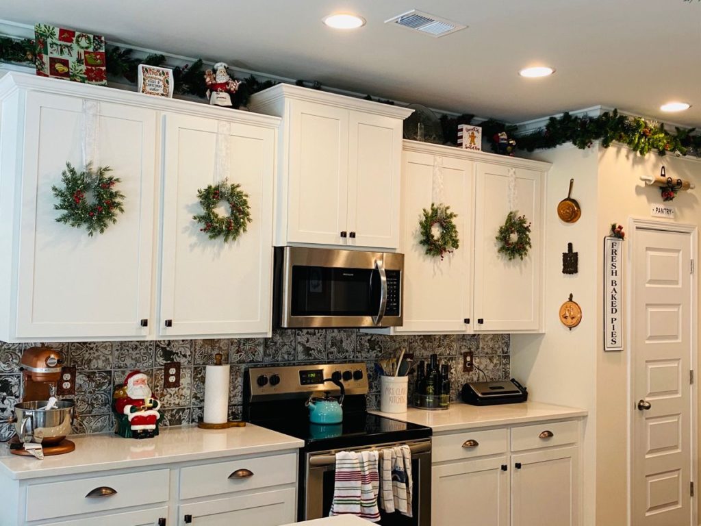 classic Christmas wreath with red and green ribbons and ornaments hanging above a kitchen sink