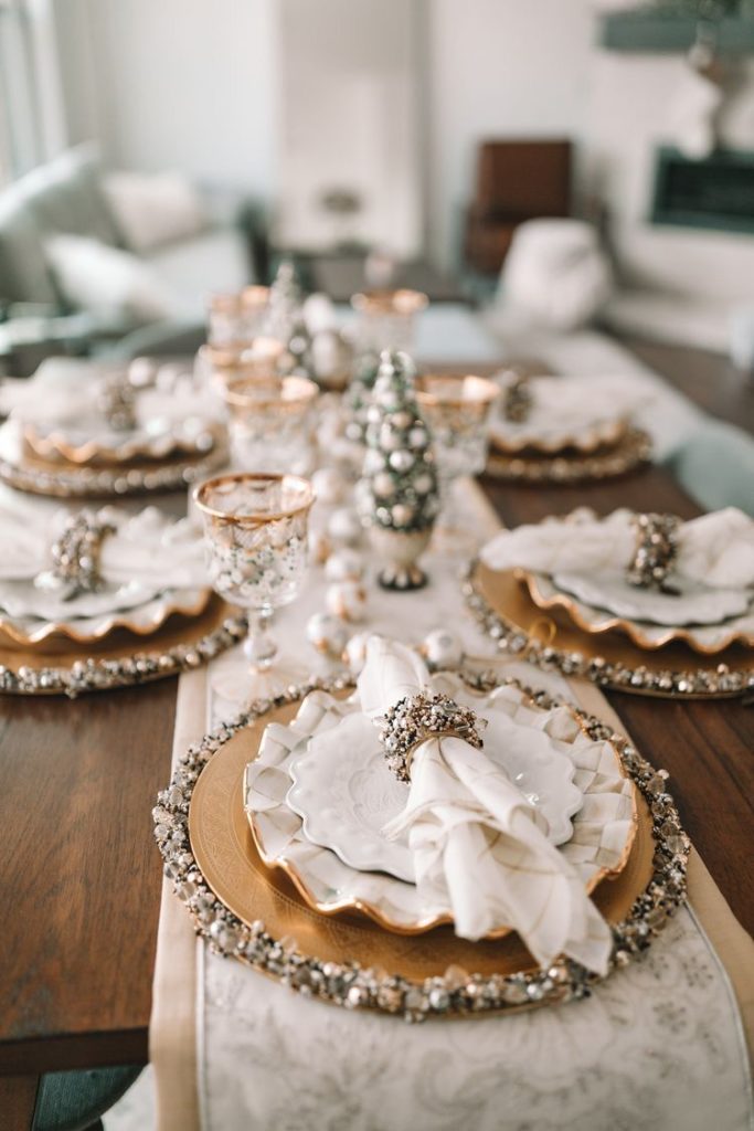 kitchen table set with a red tablecloth, green napkins, and Christmas-themed mugs