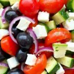 A colorful Mediterranean salad featuring tomatoes, cucumbers, feta cheese, and olives.